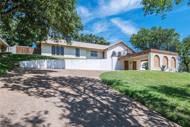 view of front of property with a balcony and a front lawn