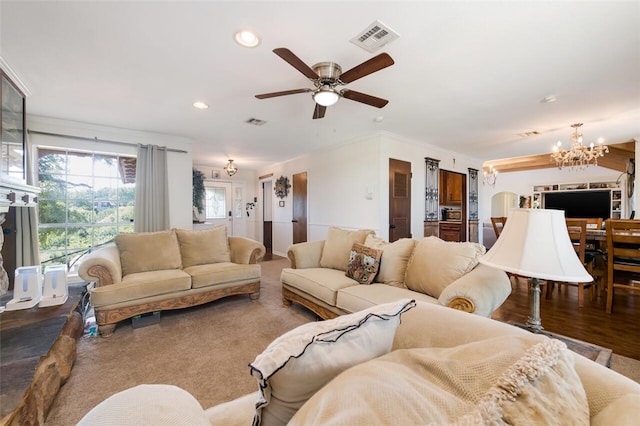 living room with ceiling fan with notable chandelier and crown molding