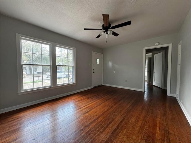 unfurnished room with a textured ceiling, ceiling fan, a healthy amount of sunlight, and dark hardwood / wood-style floors