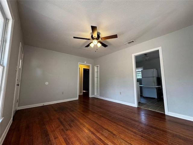 empty room with ceiling fan, dark hardwood / wood-style flooring, and a textured ceiling