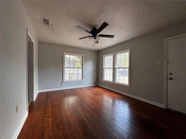 unfurnished room featuring ceiling fan, a healthy amount of sunlight, dark hardwood / wood-style flooring, and a textured ceiling