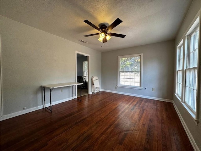 interior space featuring a textured ceiling, ceiling fan, and dark wood-type flooring