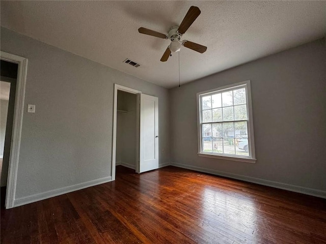 unfurnished bedroom with a closet, a textured ceiling, dark hardwood / wood-style floors, and ceiling fan