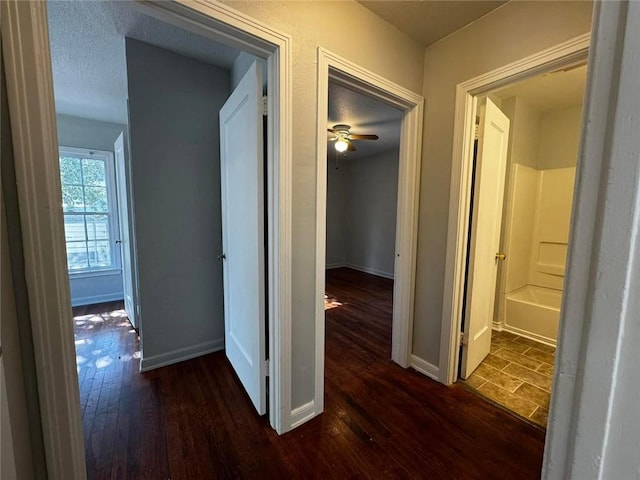 hall with a textured ceiling and dark hardwood / wood-style floors