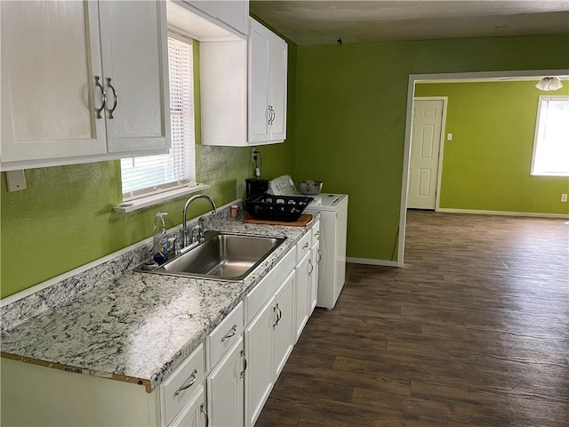 kitchen with light stone countertops, sink, washer and dryer, white cabinets, and dark hardwood / wood-style floors