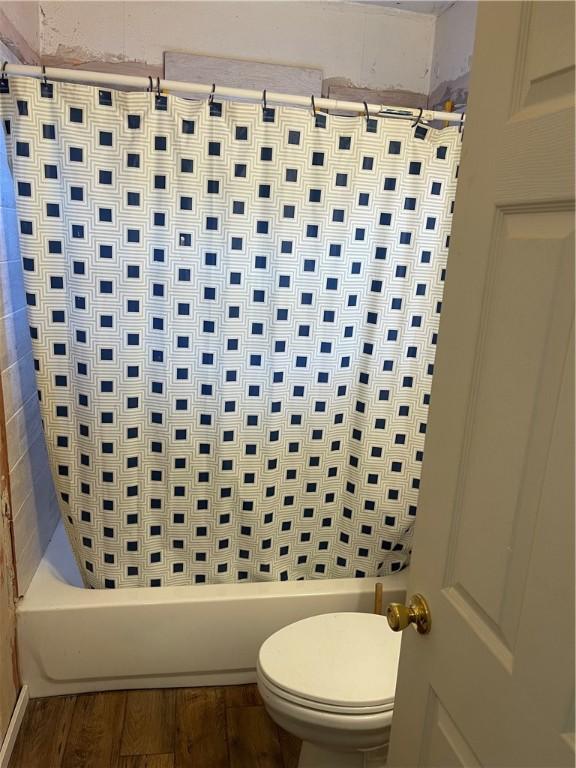 interior space featuring shower / bath combo with shower curtain, toilet, and wood-type flooring