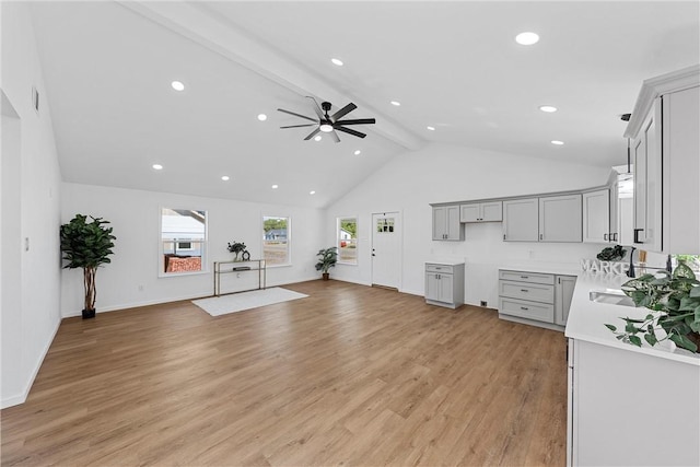 living room featuring ceiling fan, light hardwood / wood-style flooring, beamed ceiling, and high vaulted ceiling