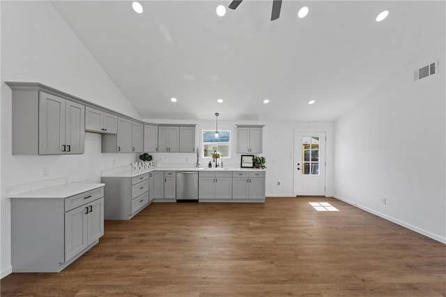 kitchen featuring gray cabinetry, dark hardwood / wood-style floors, stainless steel dishwasher, and vaulted ceiling