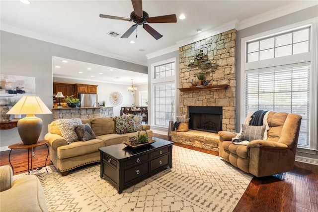 living room featuring ceiling fan with notable chandelier, a fireplace, crown molding, and light hardwood / wood-style flooring