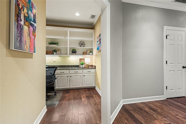 bar featuring white cabinetry, built in desk, dark wood-type flooring, and ornamental molding