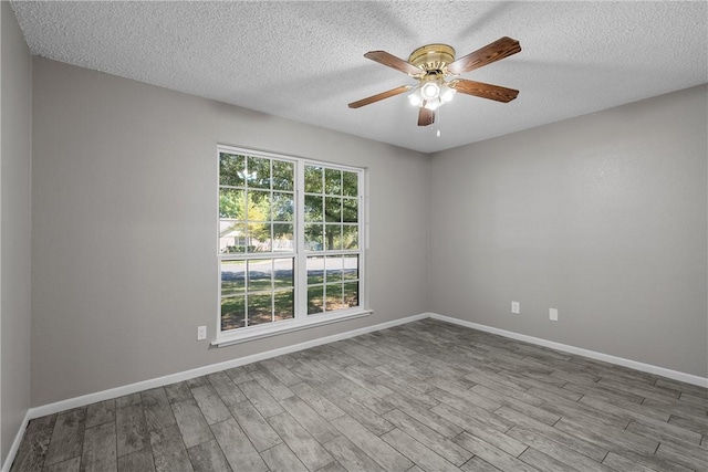 spare room featuring ceiling fan, a textured ceiling, baseboards, and wood finished floors