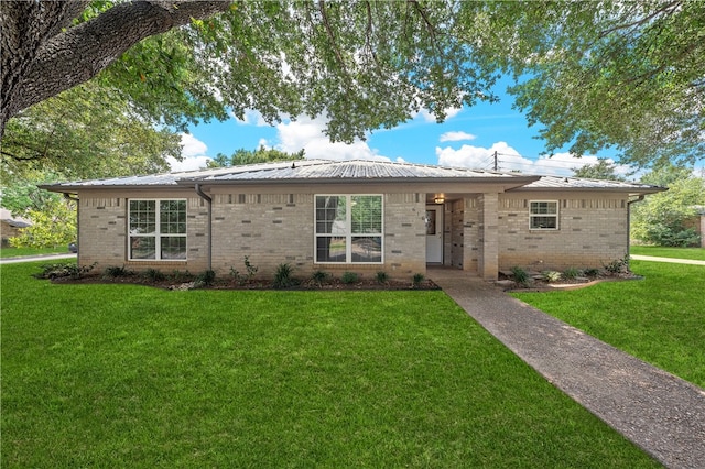 ranch-style house featuring brick siding, metal roof, and a front lawn