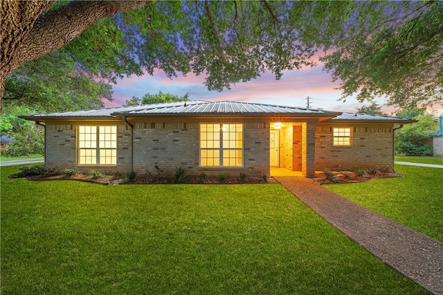 ranch-style house with a yard, brick siding, and metal roof