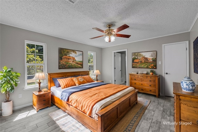 bedroom with multiple windows, a textured ceiling, and light wood finished floors