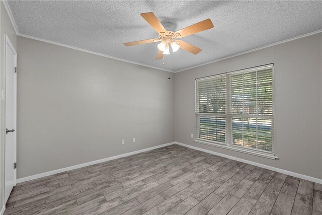 empty room with baseboards, wood finished floors, and crown molding