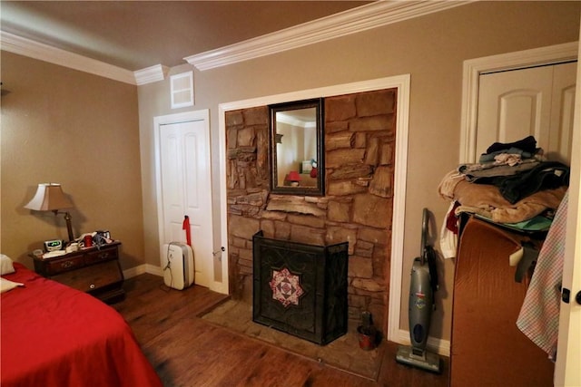 bedroom featuring a fireplace, ornamental molding, and dark wood-type flooring