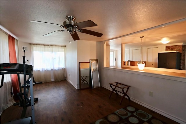 workout area featuring ceiling fan, dark hardwood / wood-style floors, and a textured ceiling