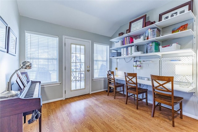 dining room with a healthy amount of sunlight, baseboards, lofted ceiling, and light wood-style floors