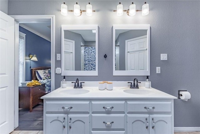 bathroom featuring double vanity, a textured wall, and a sink