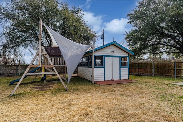 view of shed with a playground and a fenced backyard