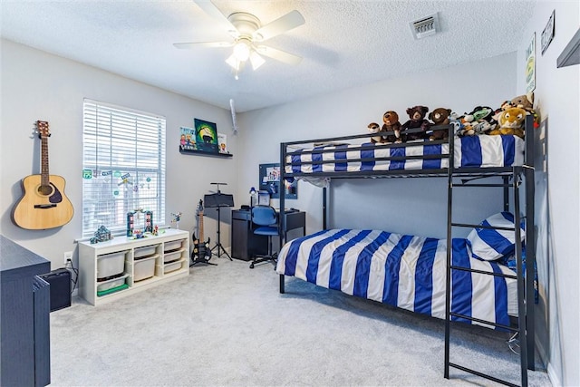 bedroom featuring ceiling fan, visible vents, carpet floors, and a textured ceiling