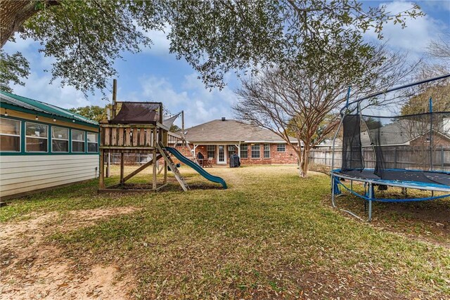 view of yard with a playground, a trampoline, and fence