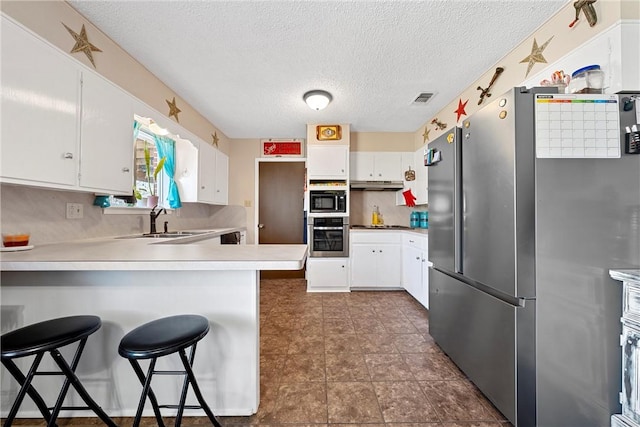 kitchen with stainless steel refrigerator, sink, kitchen peninsula, a breakfast bar, and white cabinets