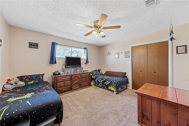 carpeted bedroom with ceiling fan, a textured ceiling, and a closet