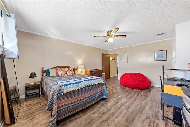 bedroom with ceiling fan, crown molding, wood-type flooring, and a textured ceiling