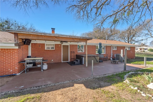 rear view of property with central AC, a patio, and a hot tub