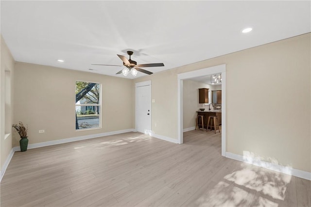 unfurnished room featuring ceiling fan, sink, and light wood-type flooring