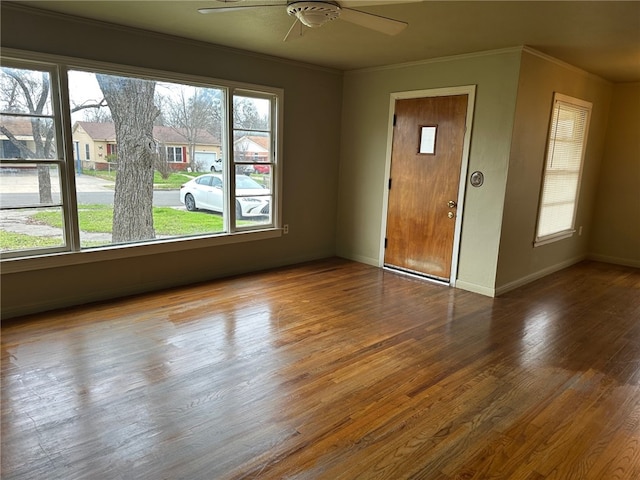 unfurnished room with ceiling fan, baseboards, a residential view, ornamental molding, and wood finished floors