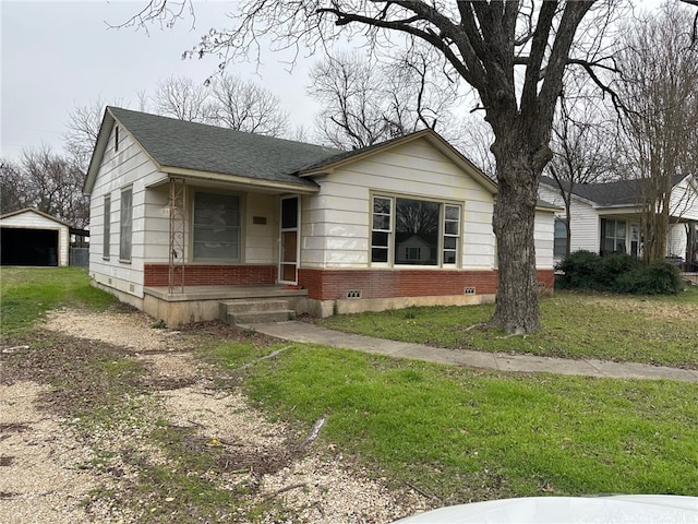 view of front of property featuring an outbuilding, driveway, a shingled roof, a front lawn, and brick siding