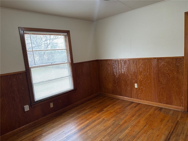 spare room with wooden walls, hardwood / wood-style floors, and wainscoting