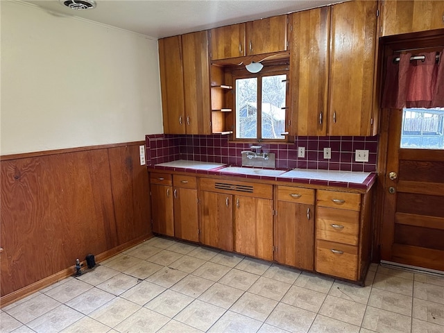 kitchen featuring wainscoting, brown cabinets, and a sink