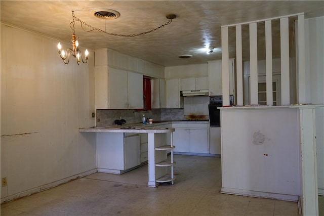 kitchen with visible vents, a peninsula, under cabinet range hood, white cabinetry, and black oven