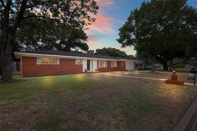 ranch-style home featuring a lawn and a garage