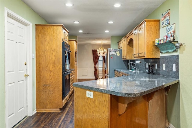 kitchen with tasteful backsplash, dark hardwood / wood-style flooring, kitchen peninsula, black double oven, and a kitchen bar