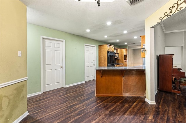 kitchen featuring kitchen peninsula, a textured ceiling, dark hardwood / wood-style flooring, and a breakfast bar