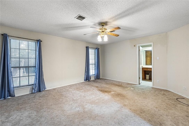 empty room with a textured ceiling, light colored carpet, and ceiling fan