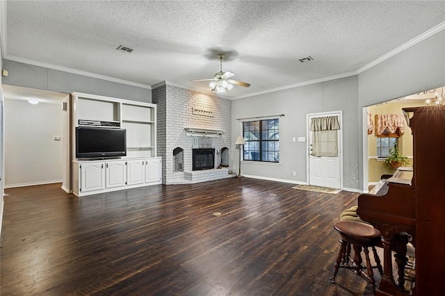 living room featuring a brick fireplace, dark hardwood / wood-style floors, ceiling fan, ornamental molding, and a textured ceiling