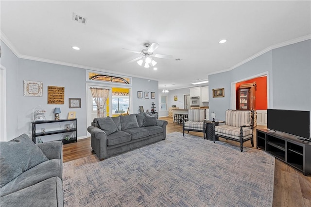 living room featuring crown molding, wood-type flooring, and ceiling fan