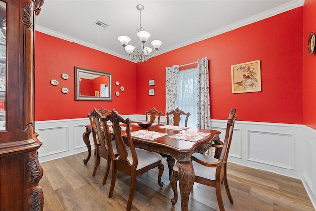 dining area featuring hardwood / wood-style floors, ornamental molding, and an inviting chandelier