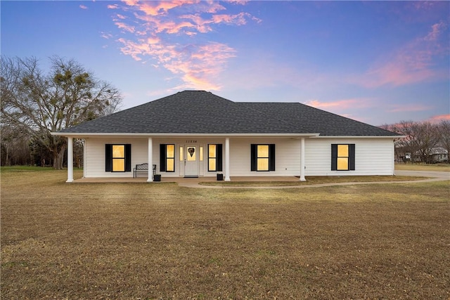 view of front of home with covered porch and a yard