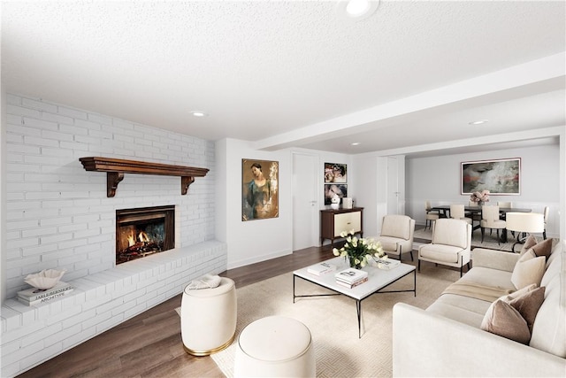 living room with hardwood / wood-style flooring, a fireplace, and a textured ceiling