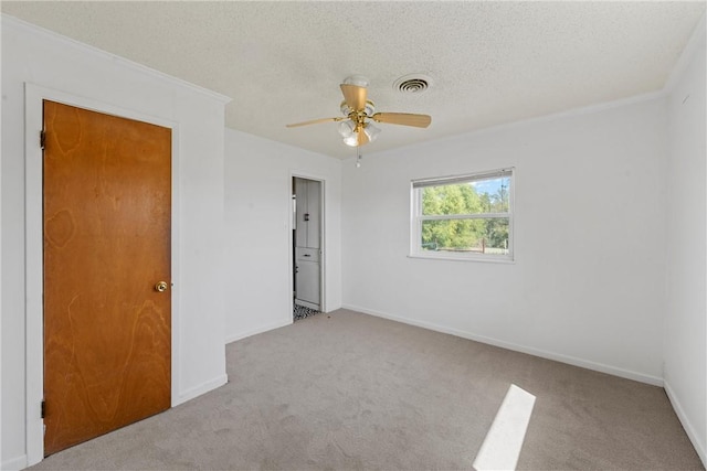 empty room featuring a textured ceiling, ceiling fan, ornamental molding, and light carpet