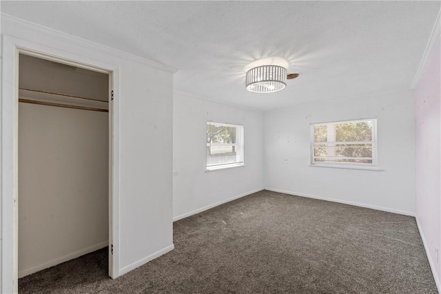 unfurnished bedroom featuring crown molding, a closet, and dark colored carpet