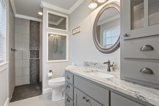 bathroom featuring vanity, tile patterned floors, toilet, ornamental molding, and tiled shower