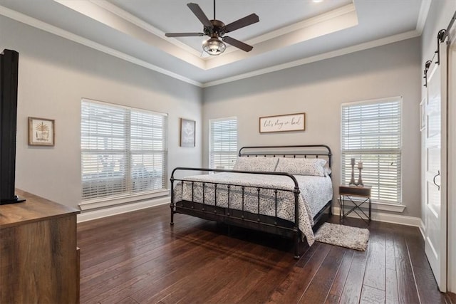 bedroom with ceiling fan, a raised ceiling, a barn door, dark hardwood / wood-style floors, and crown molding