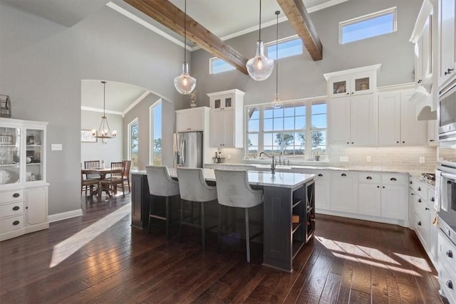 kitchen featuring white cabinetry, dark wood-type flooring, high vaulted ceiling, a kitchen island with sink, and appliances with stainless steel finishes